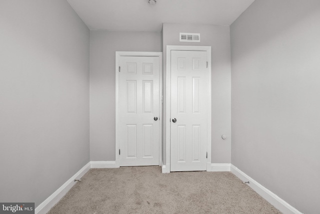 unfurnished bedroom featuring light carpet and a closet