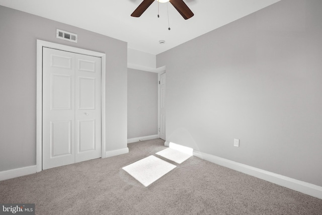 unfurnished bedroom featuring ceiling fan, light colored carpet, and a closet