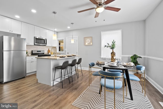 kitchen featuring light stone countertops, stainless steel appliances, dark hardwood / wood-style floors, a center island with sink, and white cabinets