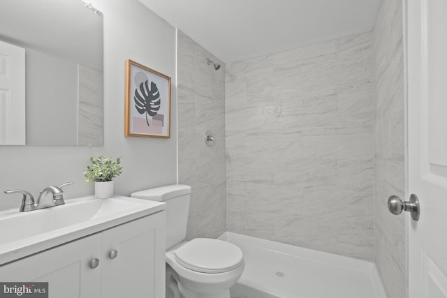 bathroom featuring tiled shower, vanity, and toilet