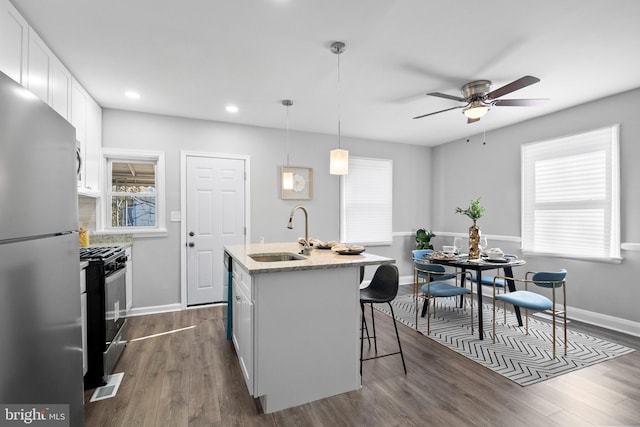 kitchen featuring white cabinetry, sink, hanging light fixtures, dark wood-type flooring, and stainless steel appliances