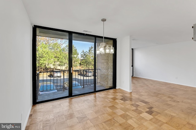 spare room featuring light parquet flooring, floor to ceiling windows, and an inviting chandelier