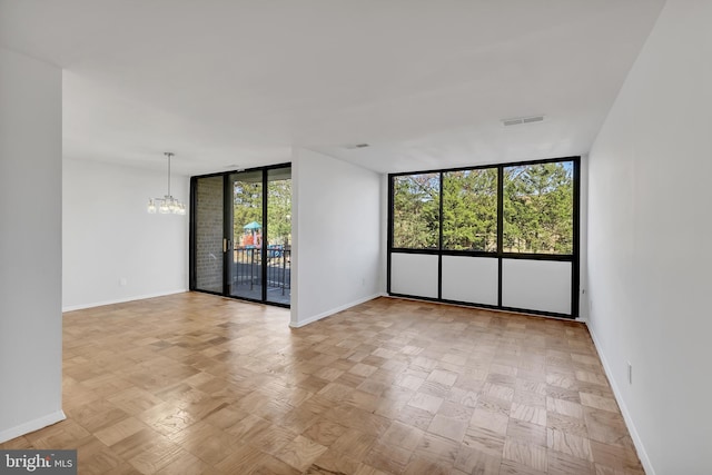 unfurnished room featuring light parquet floors, plenty of natural light, expansive windows, and an inviting chandelier