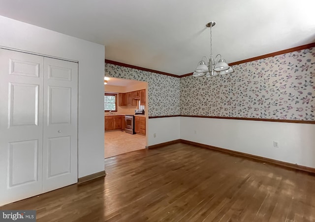 unfurnished dining area with dark wood-type flooring, sink, ornamental molding, and a notable chandelier