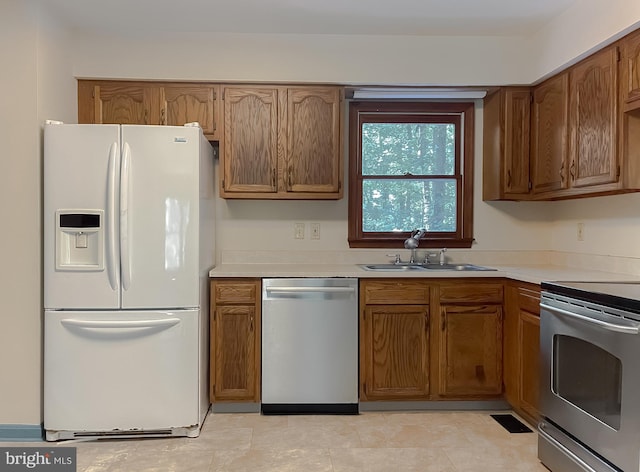 kitchen with stainless steel dishwasher, white refrigerator with ice dispenser, sink, and stove