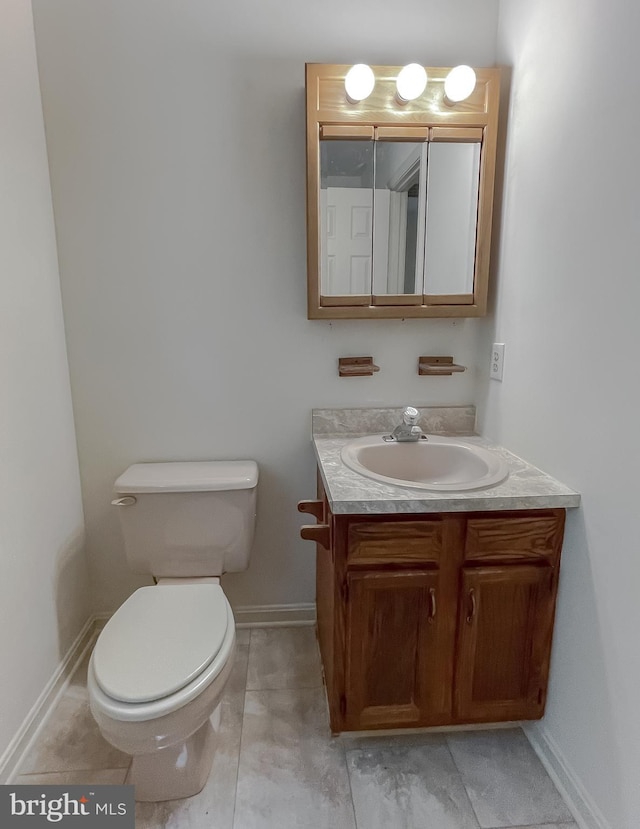 bathroom with toilet, vanity, and tile patterned floors