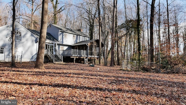 rear view of house with a wooden deck and a sunroom