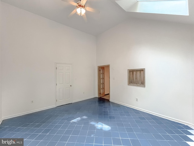 tiled spare room with ceiling fan, a skylight, and high vaulted ceiling