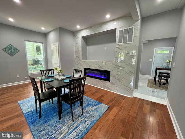 dining space with a fireplace, dark wood-type flooring, and tile walls