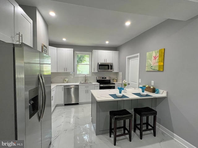 504 Cedarcroft Rd, Baltimore, MD 21212 - kitchen with stainless steel appliances, a sink, a peninsula, light marble finish flooring, and a breakfast bar