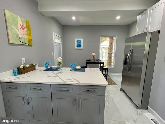 kitchen featuring gray cabinetry, white cabinets, light stone counters, and stainless steel refrigerator with ice dispenser