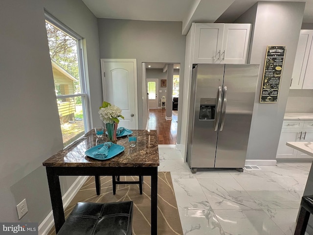 kitchen with stainless steel fridge, light wood-type flooring, and white cabinetry