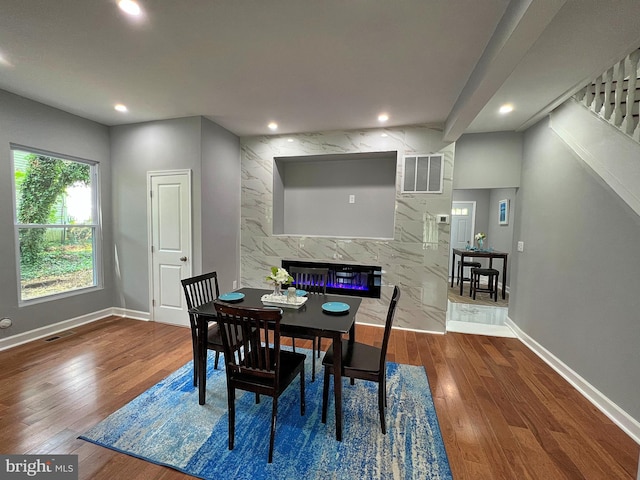 dining area with dark hardwood / wood-style floors, a fireplace, and tile walls