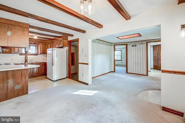 kitchen with beamed ceiling, white fridge, light carpet, and a baseboard radiator