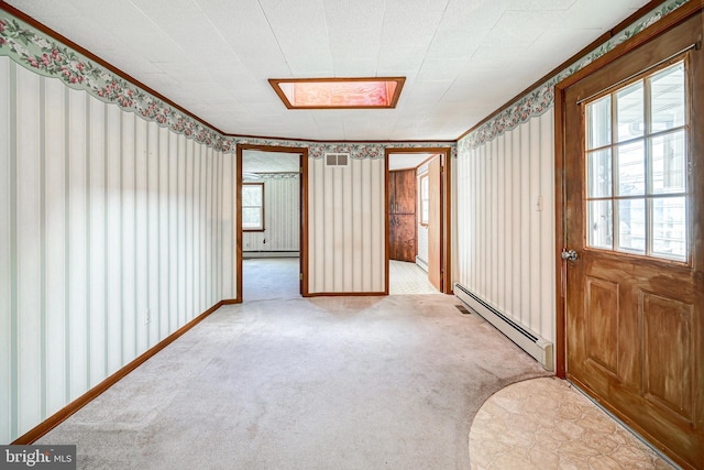 empty room featuring a skylight, light colored carpet, and a baseboard radiator