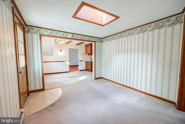 carpeted spare room with ornamental molding, a baseboard radiator, and a skylight