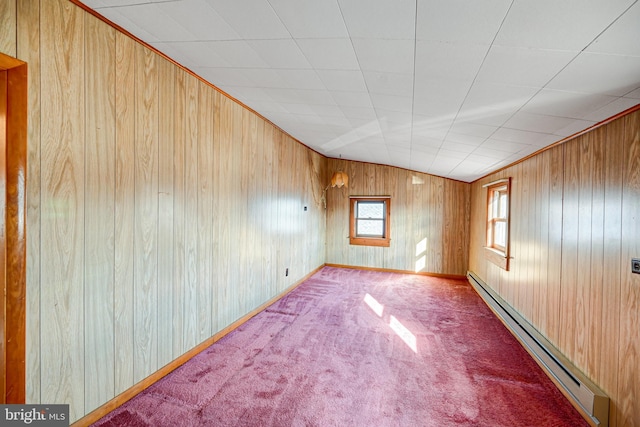 carpeted spare room with vaulted ceiling, a baseboard heating unit, and wood walls