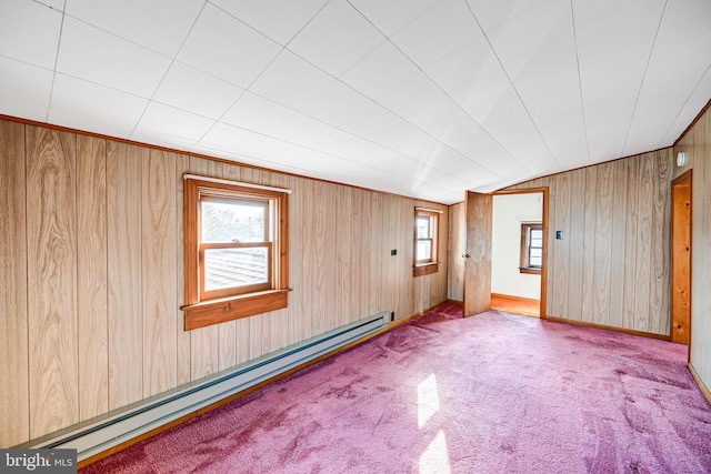 empty room featuring wooden walls, light colored carpet, and a baseboard heating unit