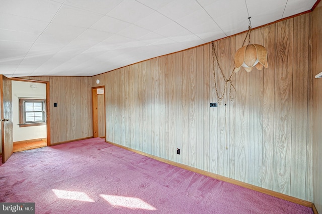 carpeted empty room with wooden walls and lofted ceiling