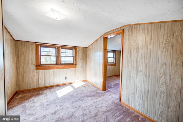 carpeted empty room with wooden walls and lofted ceiling