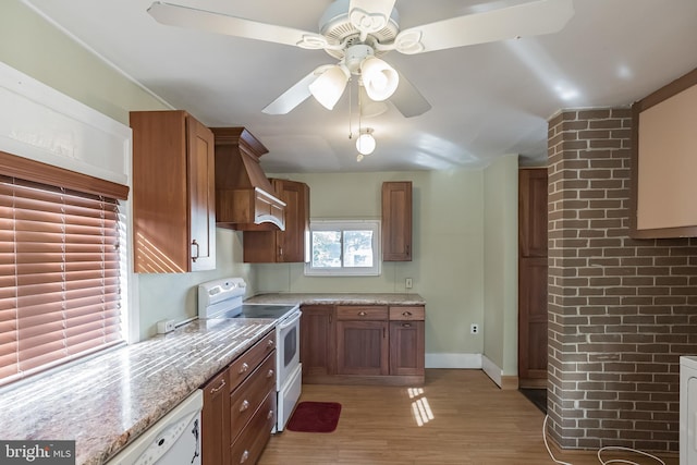 kitchen with custom exhaust hood, white appliances, ceiling fan, light stone countertops, and light hardwood / wood-style floors