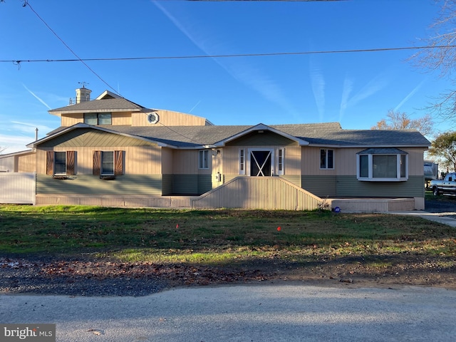 view of front of home with a shingled roof and a front yard