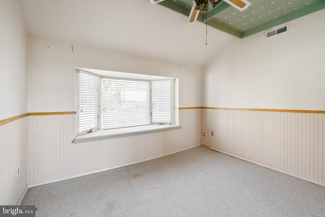 carpeted spare room featuring vaulted ceiling and ceiling fan