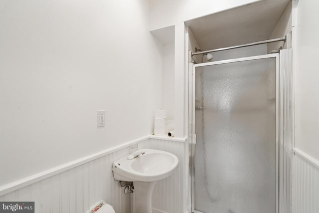 full bath with wainscoting and a shower stall