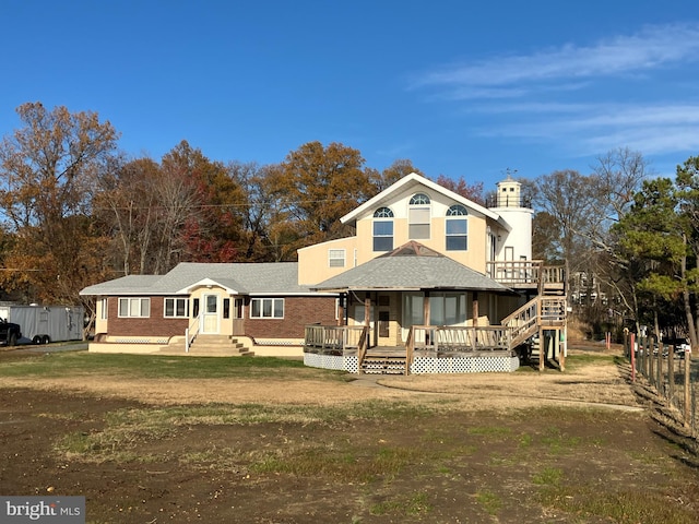 view of front of home featuring a front lawn, a wooden deck, and brick siding