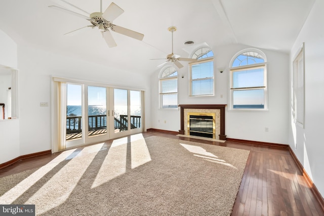 unfurnished living room featuring dark hardwood / wood-style flooring, vaulted ceiling, ceiling fan, and a tiled fireplace