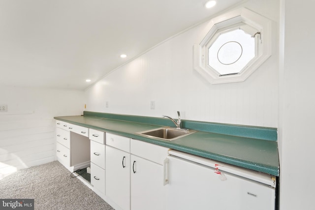 kitchen with vaulted ceiling, crown molding, carpet flooring, white cabinetry, and a sink