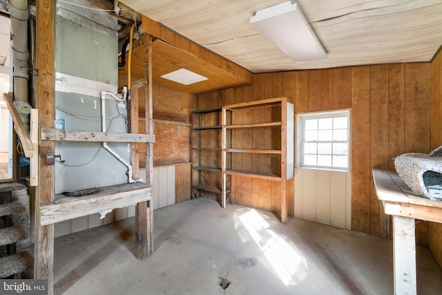 miscellaneous room featuring wood walls and unfinished concrete floors