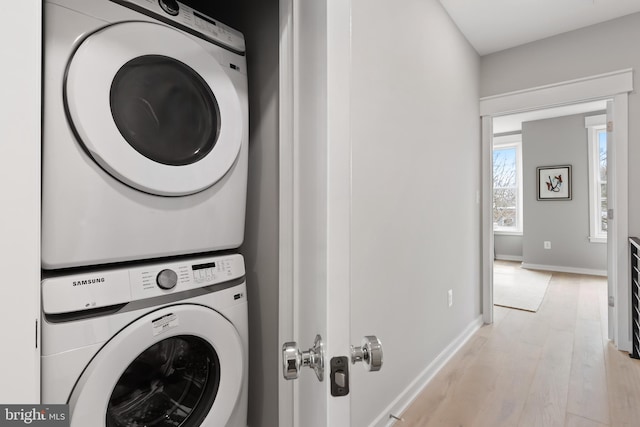 washroom featuring stacked washing maching and dryer and light hardwood / wood-style flooring