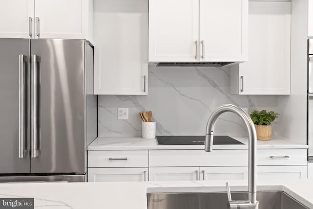 kitchen with light stone countertops, white cabinetry, tasteful backsplash, and high end refrigerator