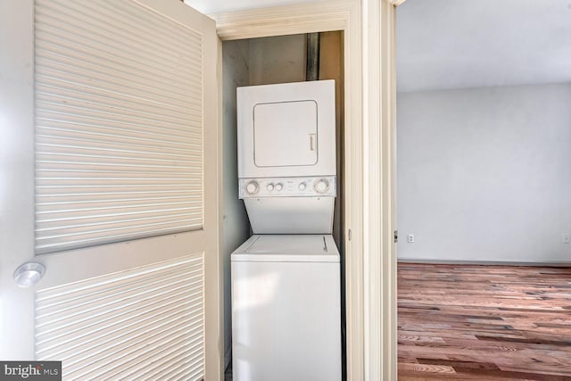 laundry area with hardwood / wood-style floors and stacked washer and clothes dryer