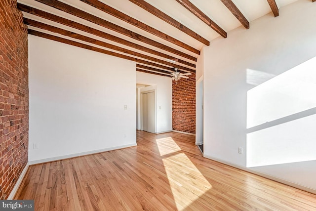 unfurnished room featuring ceiling fan, beamed ceiling, brick wall, and light wood-type flooring