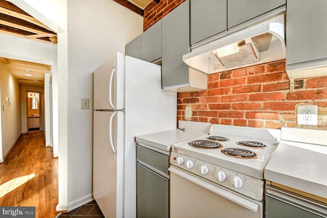 kitchen featuring gray cabinets, white appliances, dark wood-type flooring, and brick wall