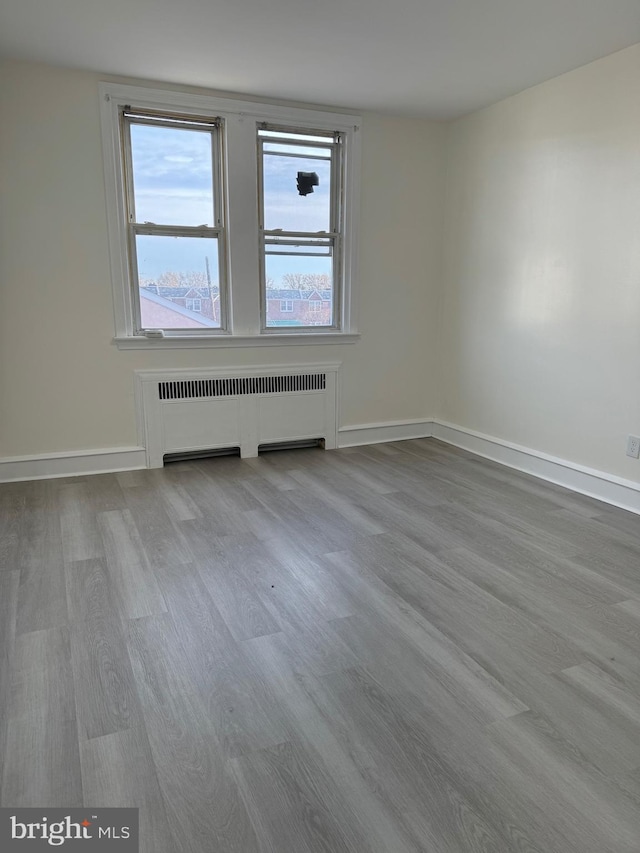 empty room with light wood-type flooring and radiator