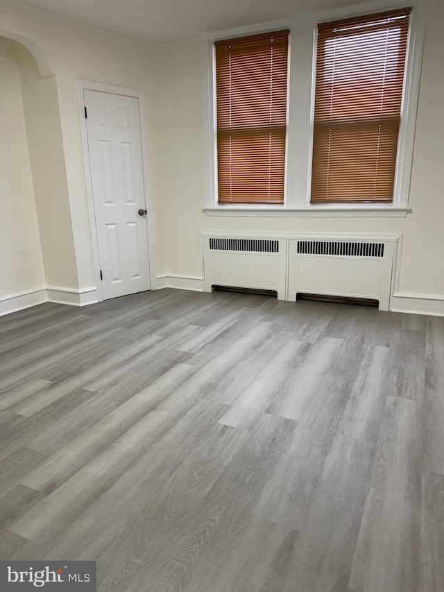 spare room featuring radiator heating unit and light hardwood / wood-style flooring