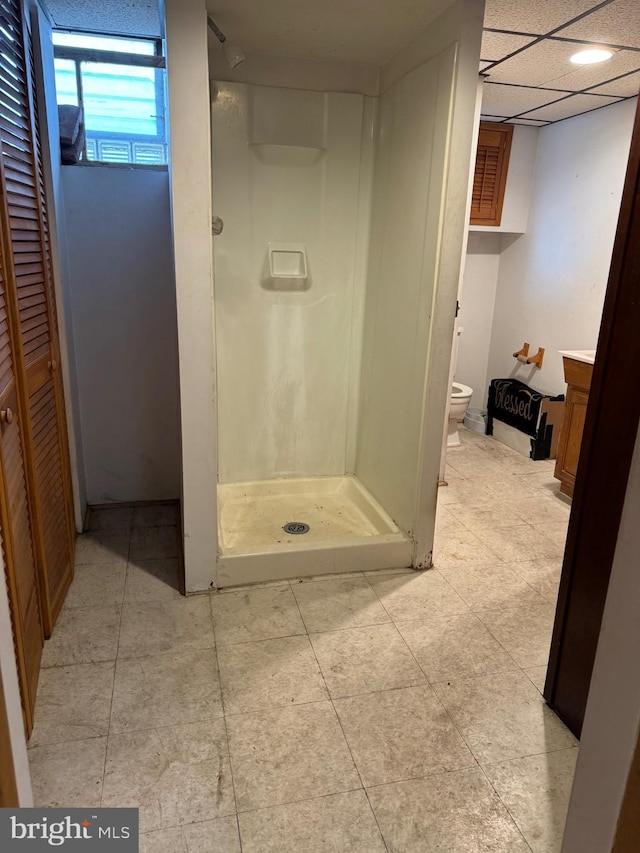 bathroom with toilet, vanity, a drop ceiling, and walk in shower