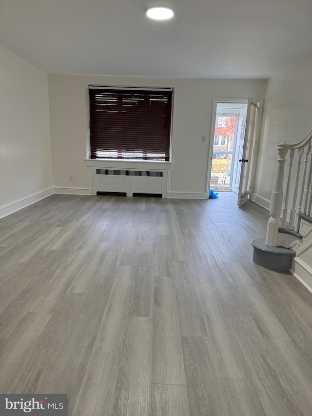 unfurnished living room with light wood-type flooring and radiator