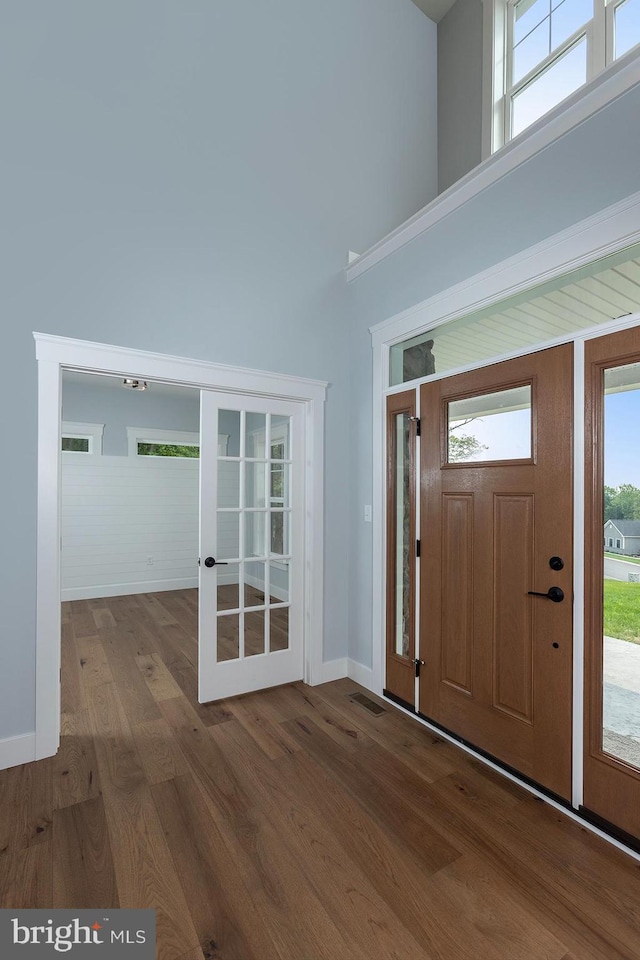 foyer entrance with wood-type flooring and a towering ceiling