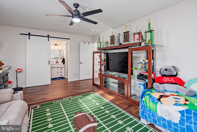 living room featuring a barn door, ceiling fan, and dark hardwood / wood-style floors