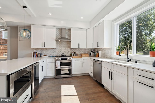 kitchen with white cabinets, wall chimney range hood, and appliances with stainless steel finishes