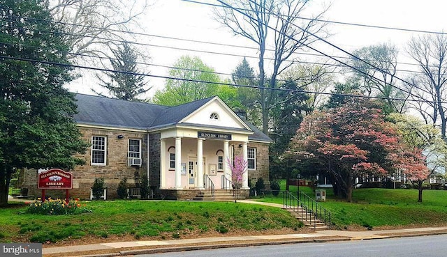 neoclassical home with a front lawn and cooling unit