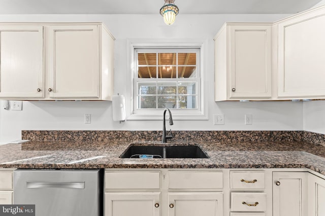 kitchen featuring white cabinetry, stainless steel dishwasher, dark stone counters, and sink