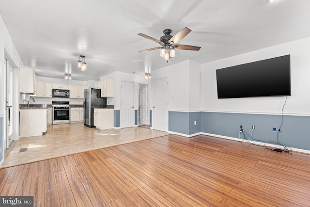 unfurnished living room featuring ceiling fan and light hardwood / wood-style floors