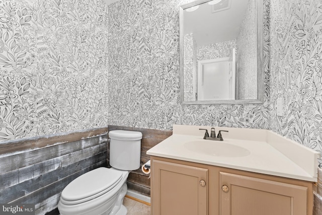 bathroom with vanity, toilet, and tile walls