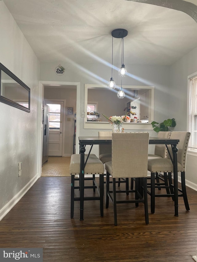 dining room with dark wood-type flooring and vaulted ceiling