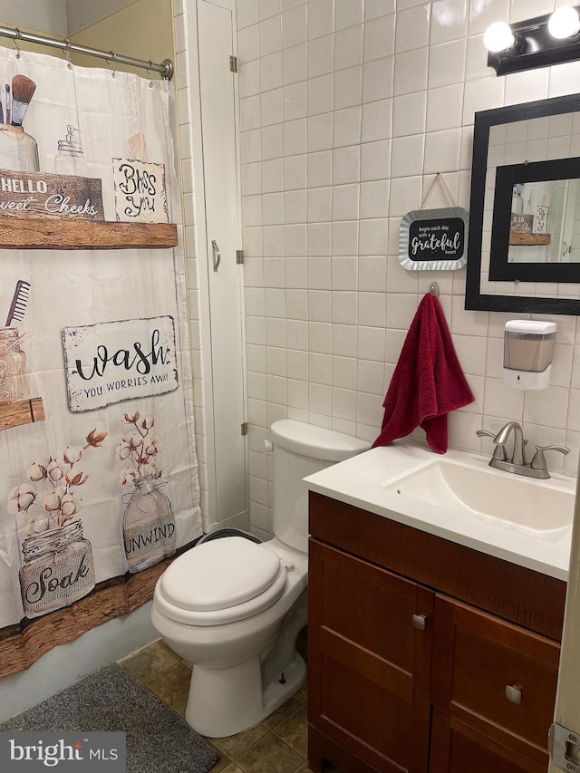 bathroom with tasteful backsplash, vanity, tile walls, tile patterned flooring, and toilet